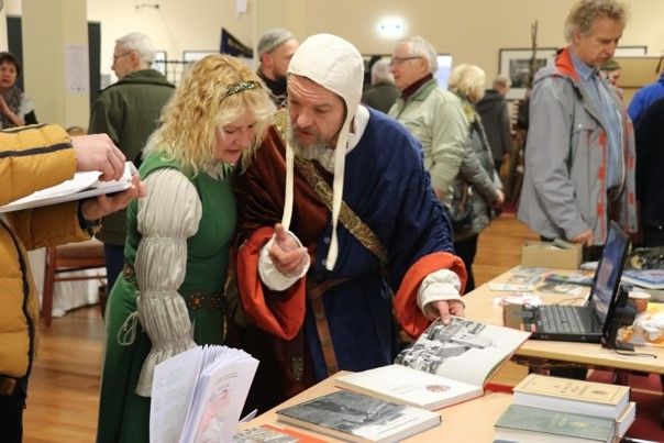 Bild: altertümlich gekleidete Menschen an einem Bücherstand